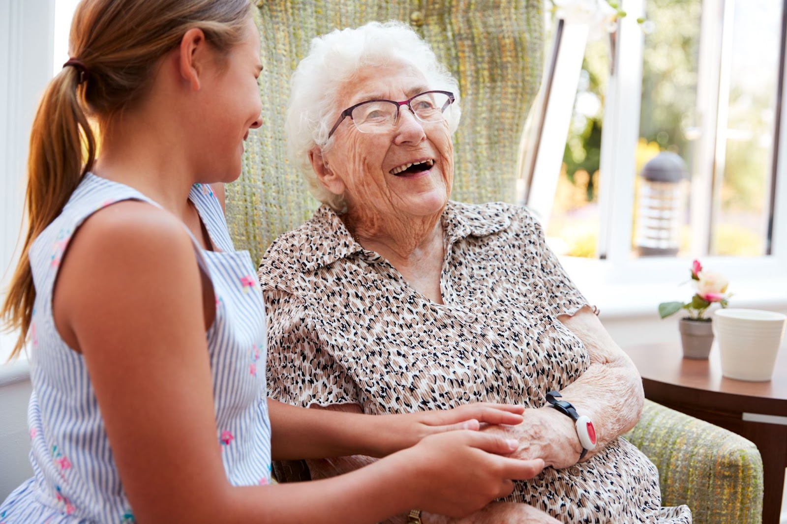 A senior's face lights up with joy as she visits with her granddaughter.