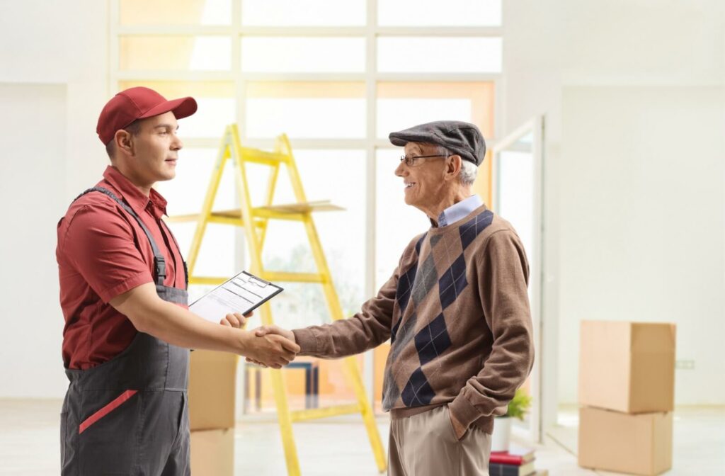 An older man smiling and shaking hands with a professional mover