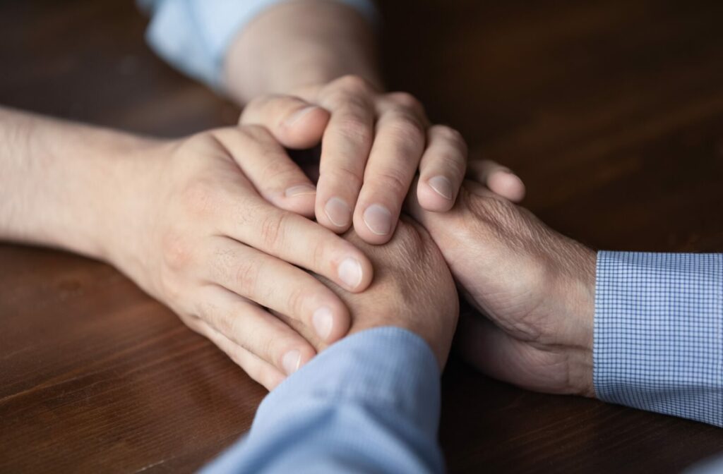 A close-up image of a person's hands over an older adult's hands.