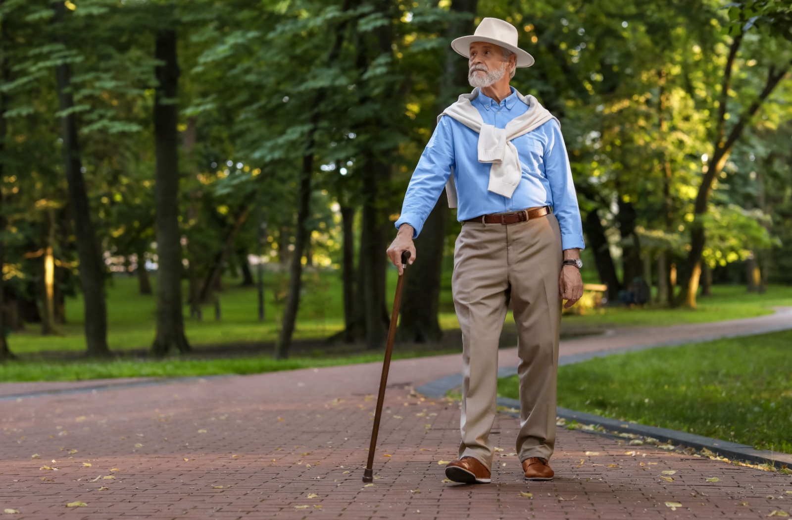 An older adult confidently goes for a walk with their cane to support them.