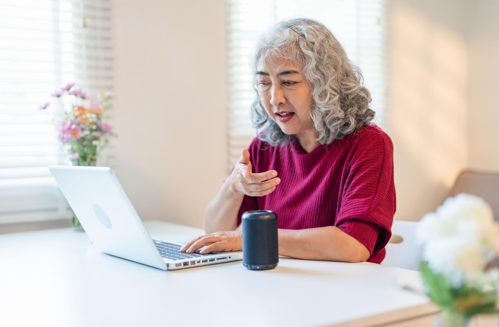 An older adult uses Alexa to help them search something on their computer.