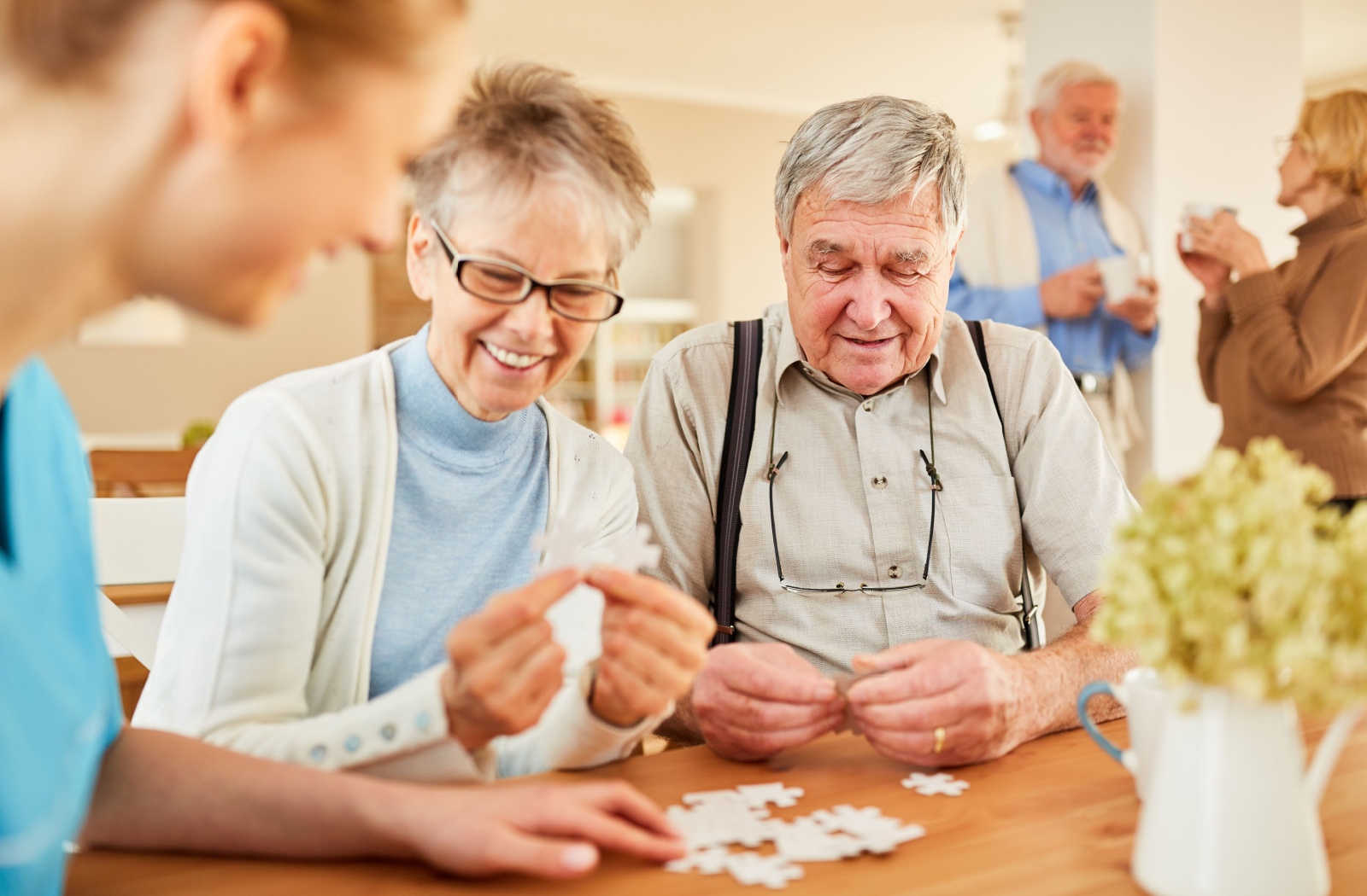A group of older adults in memory care working together to assemble a puzzle.