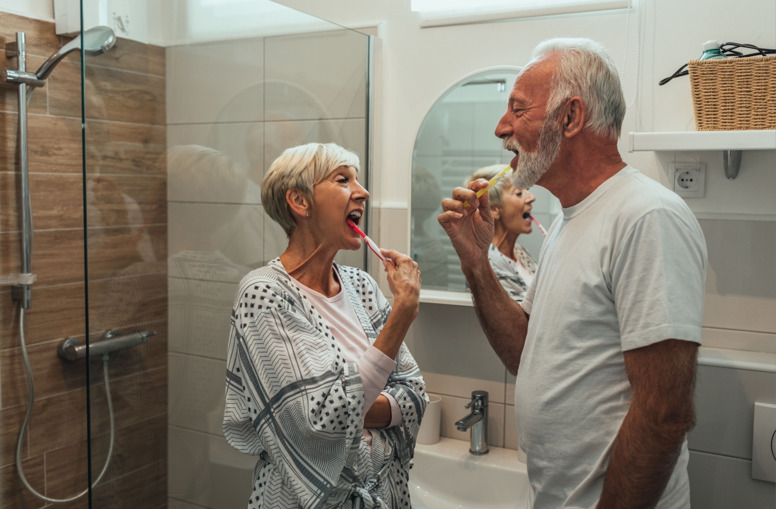 A senior couple brush their teeth together as part of a bedtime routine to help with handling dementia